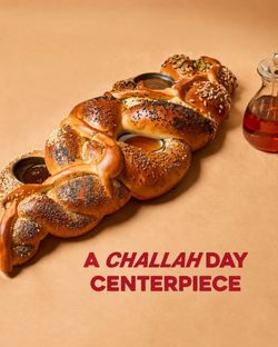 Braided challah bread centerpiece with assorted seeds and two dips, accompanied by a small jar of honey.