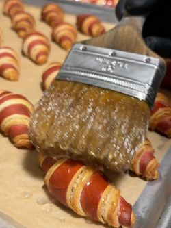 Freshly baked croissants being brushed with a glossy glaze at Breads Bakery.