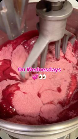 Industrial mixer blending pink and red ingredients inside a large mixing bowl at Breads Bakery