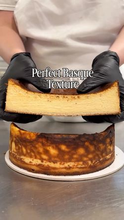 Hands holding a Basque cake with a golden-brown crust and creamy interior at Breads Bakery – Upper East Side.