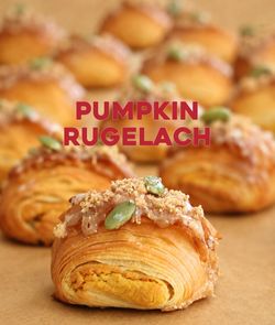 Pumpkin rugelach pastries topped with pumpkin seeds and streusel arranged in rows at Breads Bakery.
