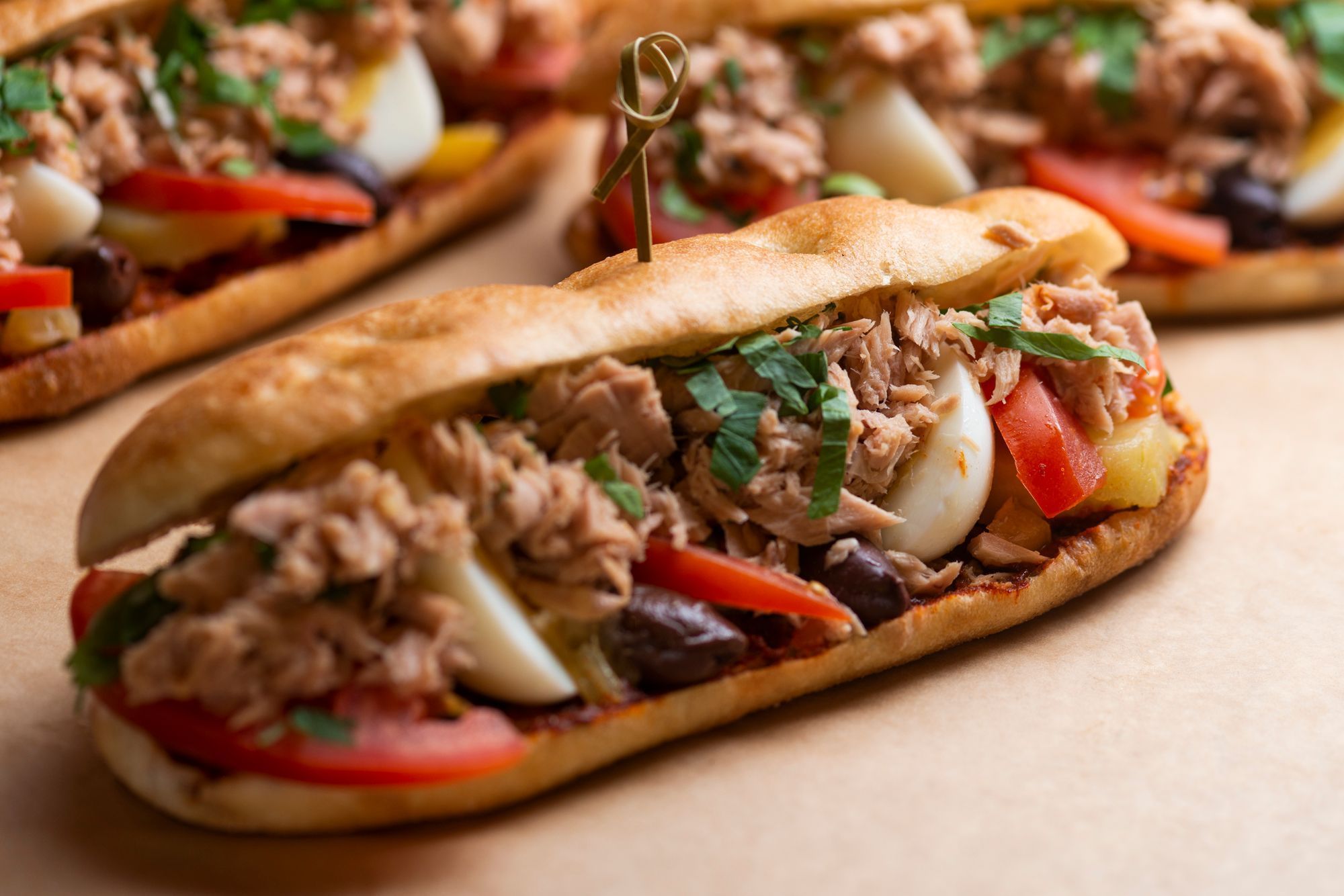Freshly made sandwiches filled with tuna, vegetables, and herbs, served on a crusty bread.