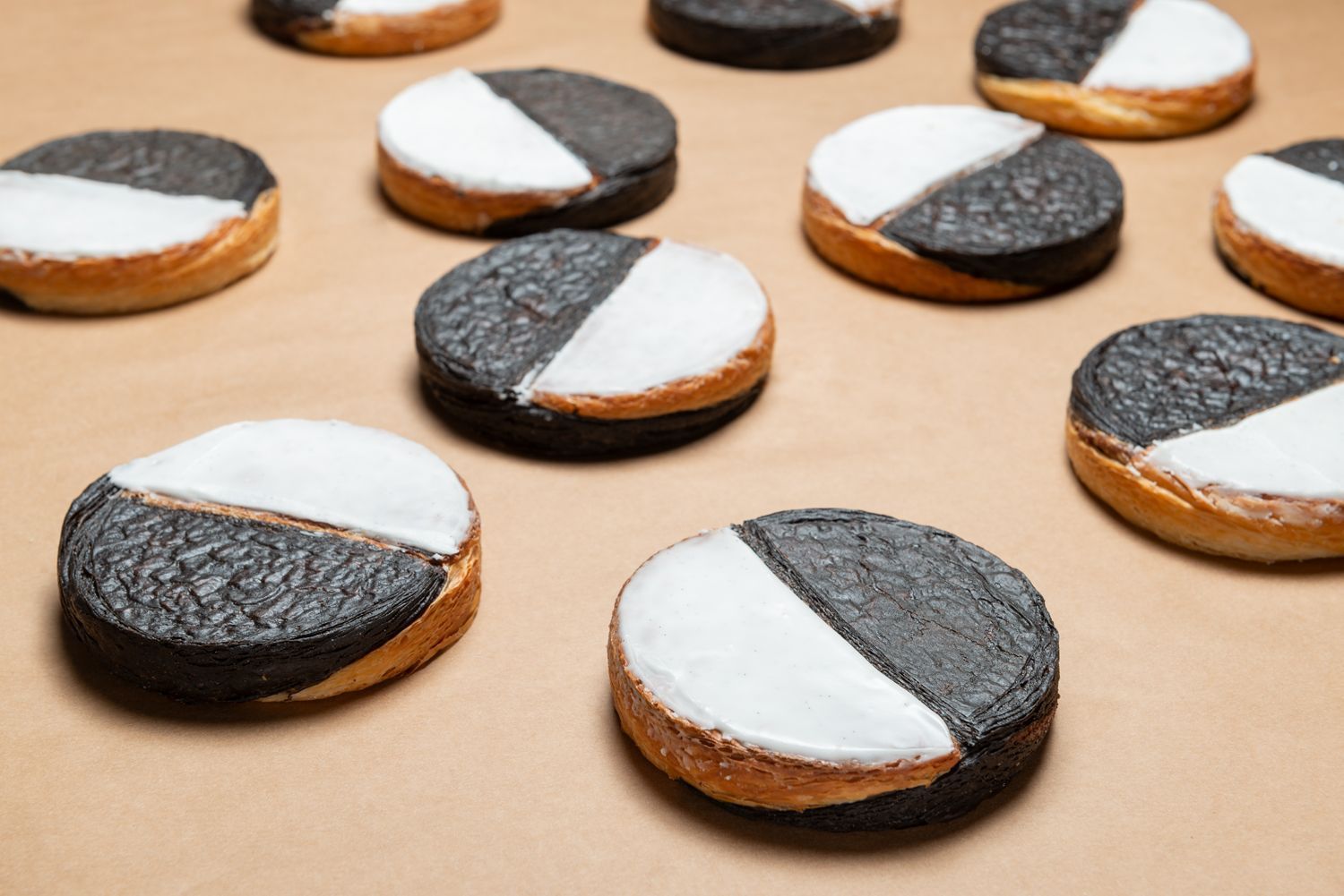 Freshly baked black and white cookies, featuring a half chocolate and half vanilla icing on each pastry.