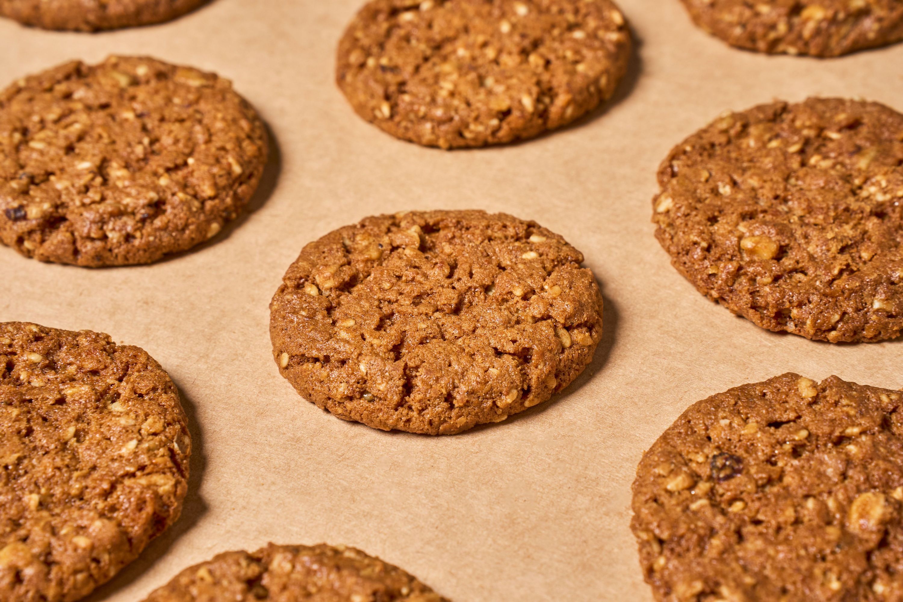 Freshly baked cookies laid out evenly on parchment paper, showcasing their textured surface.