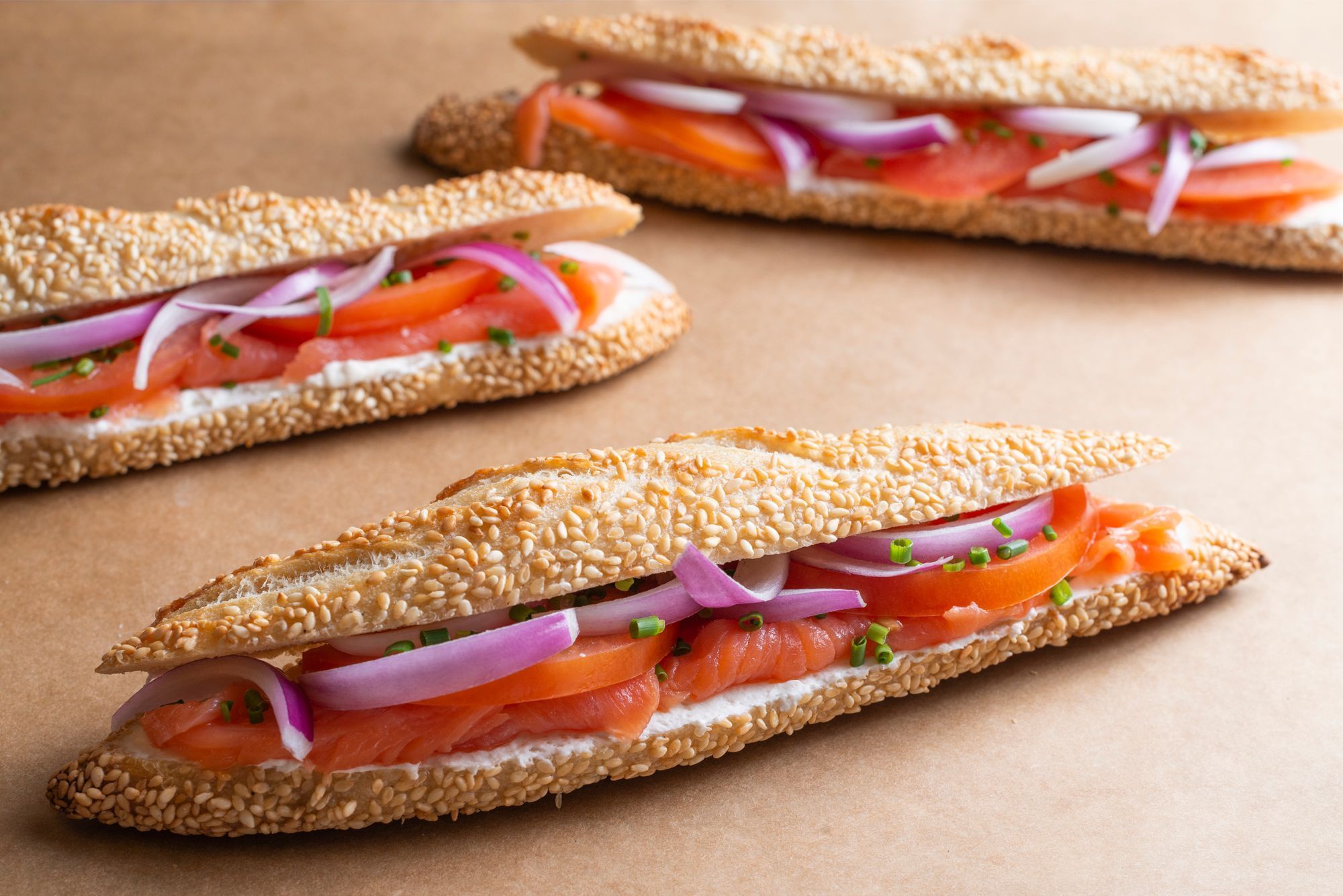 Fresh sesame bagels filled with cream cheese, smoked salmon, sliced tomatoes, and red onions.