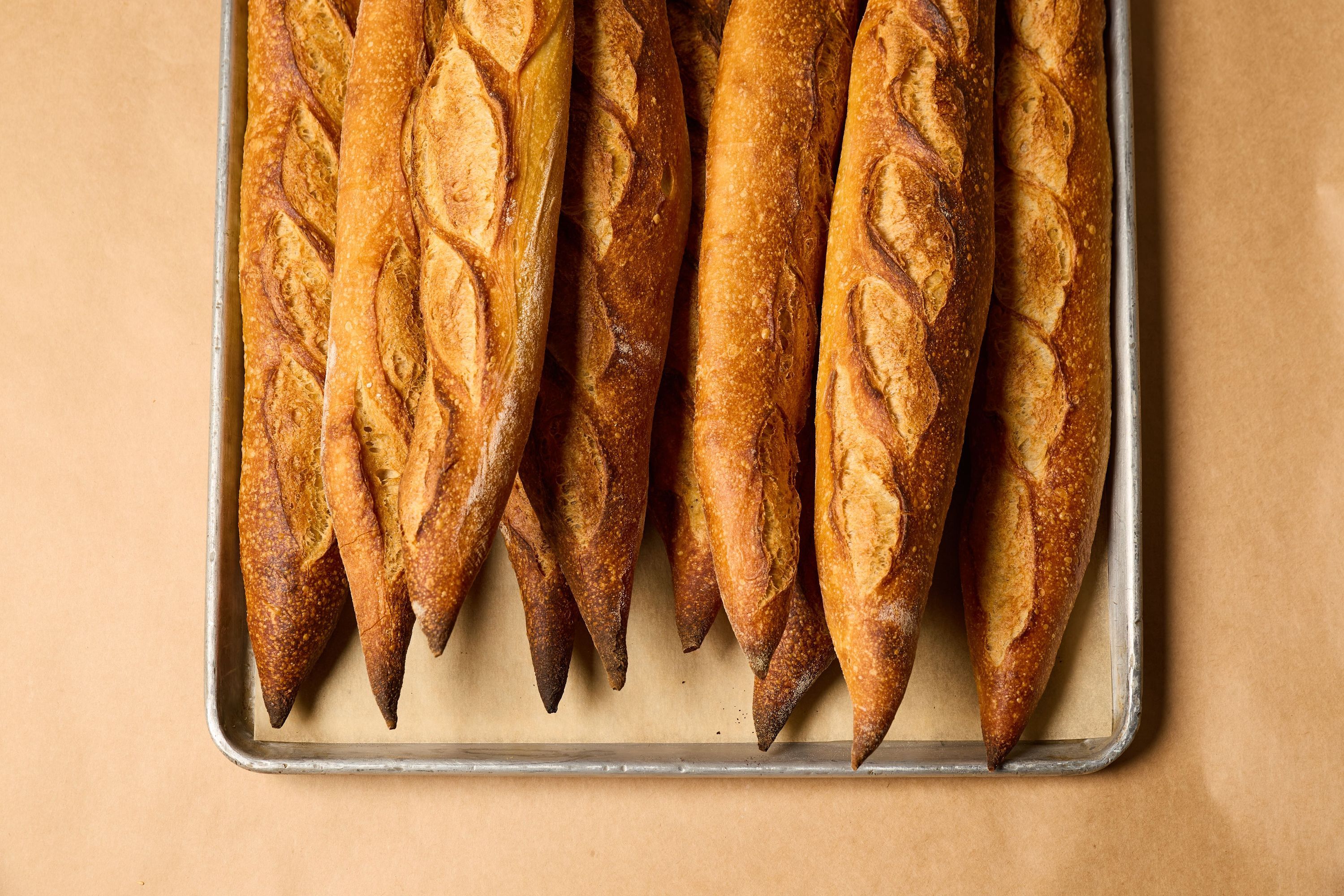 Freshly baked baguettes arranged on a tray, showcasing a golden, crusty exterior.
