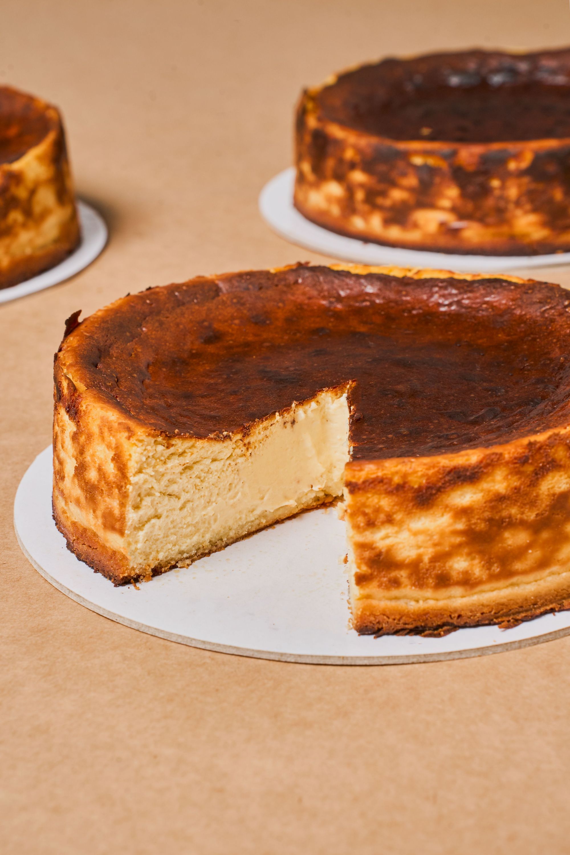 Cheesecake with a golden brown crust, partially sliced, set against a simple backdrop.