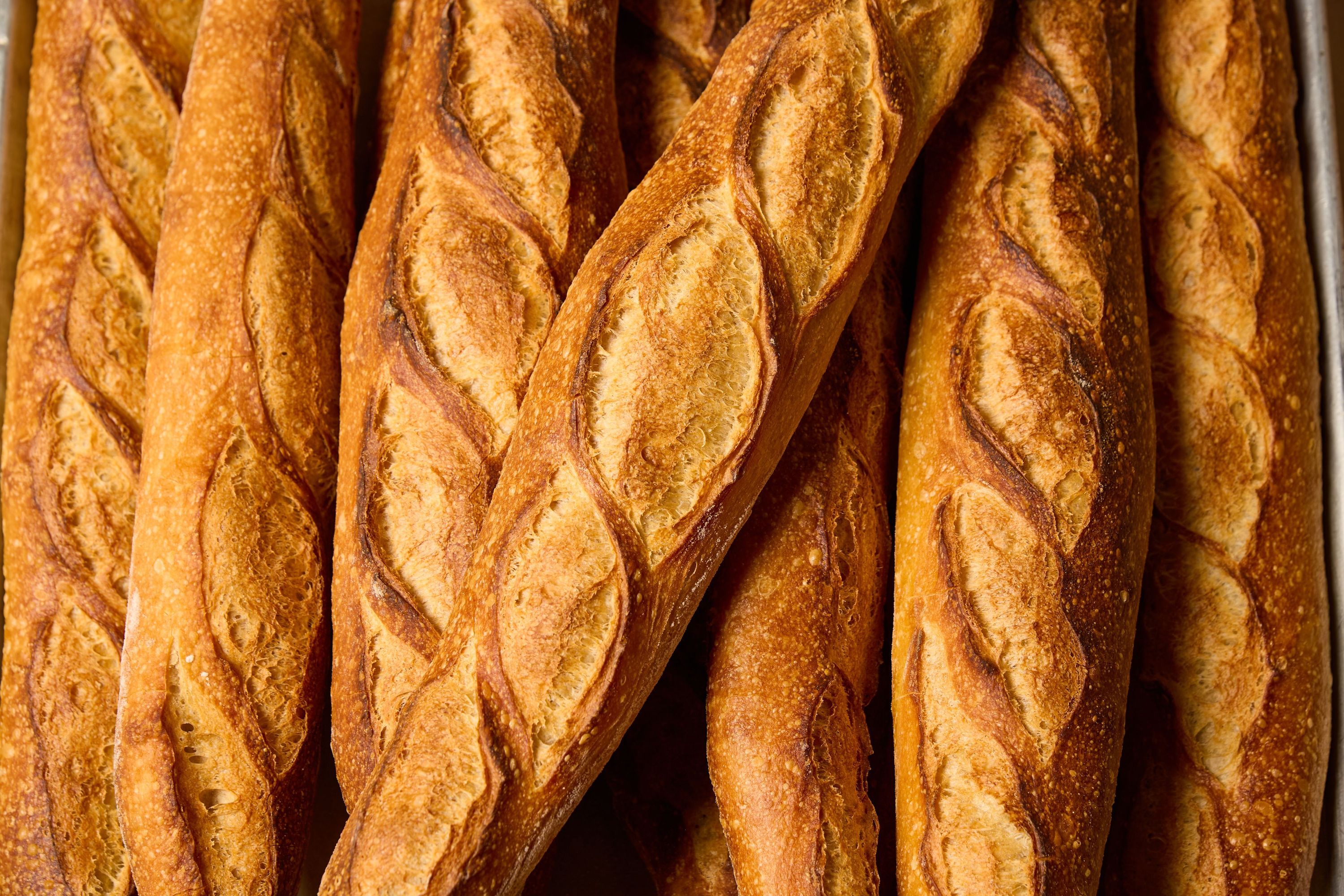 Freshly baked baguettes with a golden-brown crust, stacked closely together at Breads Bakery – Brooklyn.